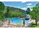 Resort-style pool with slide and lounge chairs, set against a backdrop of lush greenery and a mountain view at 7375 S Alkire St # 102, Littleton, CO 80127