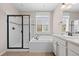 Bathroom with soaking tub, tiled shower with a glass door and vanity with dark fixtures at 6420 Agave Ave, Castle Rock, CO 80108