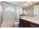 A full bathroom features a vanity, tub with shower, tiled walls and flooring, and a decorative mirror at 9432 La Quinta Way, Lone Tree, CO 80124