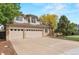 Three-car garage with ample driveway space, complemented by a well-maintained lawn and mature trees at 9432 La Quinta Way, Lone Tree, CO 80124