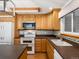 Well-lit kitchen featuring warm oak cabinets, dark counter tops, and modern white appliances at 945 Emerald St, Broomfield, CO 80020