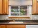 Oak cabinets accent the kitchen sink and decorative tile backsplash with a view to the backyard at 945 Emerald St, Broomfield, CO 80020