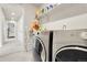 Modern laundry room with gray front load washer and dryer with access to hallway and bedroom at 6484 N Ceylon Ct, Denver, CO 80249