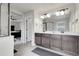Bright main bathroom featuring a double sink vanity with views to the glass enclosed shower at 6484 N Ceylon Ct, Denver, CO 80249