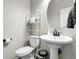 Clean and modern powder room with pedestal sink, round mirror, and minimalist decor at 6484 N Ceylon Ct, Denver, CO 80249