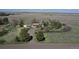 Peaceful aerial of a quaint home featuring a gravel driveway and mature trees, nestled in a private, grassy setting at 7409 S County Road 157, Strasburg, CO 80136