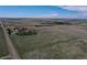 Aerial view of the property showcasing a farmhouse surrounded by trees and wide-open land under a bright sky at 7409 S County Road 157, Strasburg, CO 80136