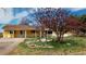 Charming single-story home with a welcoming porch, a gravel driveway, and mature flowering trees in the front yard at 7409 S County Road 157, Strasburg, CO 80136