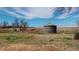 Water tank in a rural field with a metal fence and vast open land under a blue sky with scattered clouds at 7409 S County Road 157, Strasburg, CO 80136