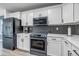 Modern kitchen featuring stainless steel appliances, white cabinetry, and a mosaic tile backsplash at 7132 Eagle Rock Dr, Littleton, CO 80125