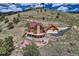 An aerial view showcases a log home with outdoor living spaces set against a scenic backdrop at 401 Raptor Point Rd, Golden, CO 80403