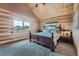 Log-walled bedroom with carpet, decorative bed, and a window view of the surrounding mountain landscape at 401 Raptor Point Rd, Golden, CO 80403