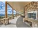 An expansive covered patio with stone pillars and fireplace offers stunning mountain views and rustic charm at 401 Raptor Point Rd, Golden, CO 80403