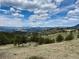 Breathtaking view of rolling hills and snow-capped mountains under a vibrant blue sky with scattered clouds at 401 Raptor Point Rd, Golden, CO 80403