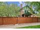 Beautiful two-story brick home with green trim, fenced yard, and mature trees at 2201 Cherry St, Denver, CO 80207
