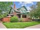 Charming two-story home featuring a brick facade, green trim, a well-manicured lawn, and mature trees at 2201 Cherry St, Denver, CO 80207
