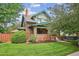 Charming two-story home featuring a brick facade, green trim, a well-manicured lawn, and mature trees at 2201 Cherry St, Denver, CO 80207
