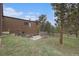 Back of home shows walkout basement, chain link enclosure and brown wood siding at 22453 Hillcrest Cir, Golden, CO 80401