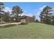 View of detached garage with driveway on grassy lot with sparse trees and shrubbery at 22453 Hillcrest Cir, Golden, CO 80401