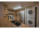 A cozy kitchen featuring stainless appliances, light cabinets, and stacked washer/dryer at 12208 W Dorado Pl # 207, Littleton, CO 80127