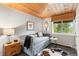 This room showcases a charming daybed, wood ceiling, and natural light from the window offering a relaxing retreat at 592 Brook Dr, Idaho Springs, CO 80452