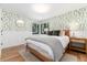 Inviting bedroom with leaf-patterned wallpaper, hardwood floors, and a cozy bed with green pillows at 1065 S Monroe St, Denver, CO 80209