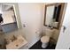 Half bathroom featuring a toilet, vanity, and a woven-framed mirror at 17747 E 54Th Ave, Denver, CO 80249
