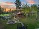 Expansive property with a fire pit, patio, trampoline, and mature trees at sunset at 34089 Woodland Dr, Evergreen, CO 80439