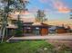 Stunning home exterior featuring modern architecture, natural wood accents, and mountain views at sunset at 34089 Woodland Dr, Evergreen, CO 80439