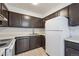 Functional kitchen featuring dark wood cabinets, stainless steel appliances, and neutral countertops at 12037 E Harvard Ave # 104, Aurora, CO 80014