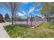 Community tennis court surrounded by green grass and mature trees under blue skies at 12037 E Harvard Ave # 104, Aurora, CO 80014