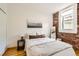 Cozy bedroom with exposed brick wall, hardwood floors, a comfortable bed, and ample natural light at 1425 N Washington St # 104, Denver, CO 80203