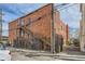 Back exterior of brick apartment building with gated entry and stairs leading to upper-level units at 1425 N Washington St # 104, Denver, CO 80203
