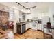Modern kitchen with white cabinets, stainless sink, hardwood floors, and adjacent living space with exposed brick at 1425 N Washington St # 104, Denver, CO 80203