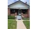 Charming brick home featuring a covered front porch and well-maintained lawn and walkway at 4654 Bryant St, Denver, CO 80211
