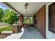 Relaxing covered front porch featuring a wooden swing and brick support columns with a view of the neighborhood at 4654 Bryant St, Denver, CO 80211