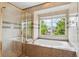 Elegant bathroom with granite-surround soaking tub, glass shower, and a sun-filled window at 18027 E Ida Dr, Centennial, CO 80015
