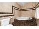 Luxurious bathroom with an elegant soaking tub with marble steps and brown-tan decorative tiling at 18027 E Ida Dr, Centennial, CO 80015