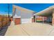 Detached two-car garage with white door and brick accents; includes a covered outdoor patio at 7651 Shoshone St, Denver, CO 80221