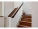 Close-up view of a staircase with hardwood steps and a dark wood railing against white walls at 4035 Fenton Ct, Wheat Ridge, CO 80212