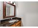 Half bathroom featuring a granite countertop, framed mirror, and light wood cabinets at 4821 N Silverlace Dr, Castle Rock, CO 80109