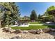 Backyard features outdoor seating, large trees, faux grass, and rocks at 3791 Charterwood Cir, Highlands Ranch, CO 80126