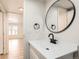 Bathroom featuring white vanity, modern black faucet, round mirror, and light wood-look flooring at 311 Harrison Ave, Fort Lupton, CO 80621
