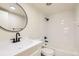 Modern bathroom featuring new fixtures, a round mirror, and a shower-tub combo at 311 Harrison Ave, Fort Lupton, CO 80621