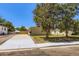 Cozy single-story home with a well-manicured lawn, mature trees, and a concrete driveway under a clear blue sky at 311 Harrison Ave, Fort Lupton, CO 80621