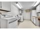 Well-lit laundry room equipped with a washer, dryer, utility sink, and ample storage space at 12423 W 68Th Ave, Arvada, CO 80004