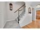 Carpeted staircase with wooden handrail and white spindles, complemented by hardwood flooring at the base at 12423 W 68Th Ave, Arvada, CO 80004