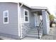 Inviting covered front porch featuring concrete steps, dark metal railing, rock facade, and light gray siding at 4460 Columbine St, Denver, CO 80216