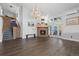 Open living room boasts dark hardwood floors, a brick fireplace, and a stunning chandelier at 11039 Roxborough Dr, Littleton, CO 80125