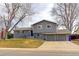 Inviting gray split-level home with a three-car garage and a well-manicured lawn, perfect for suburban living at 2136 S Balsam Ct, Lakewood, CO 80227